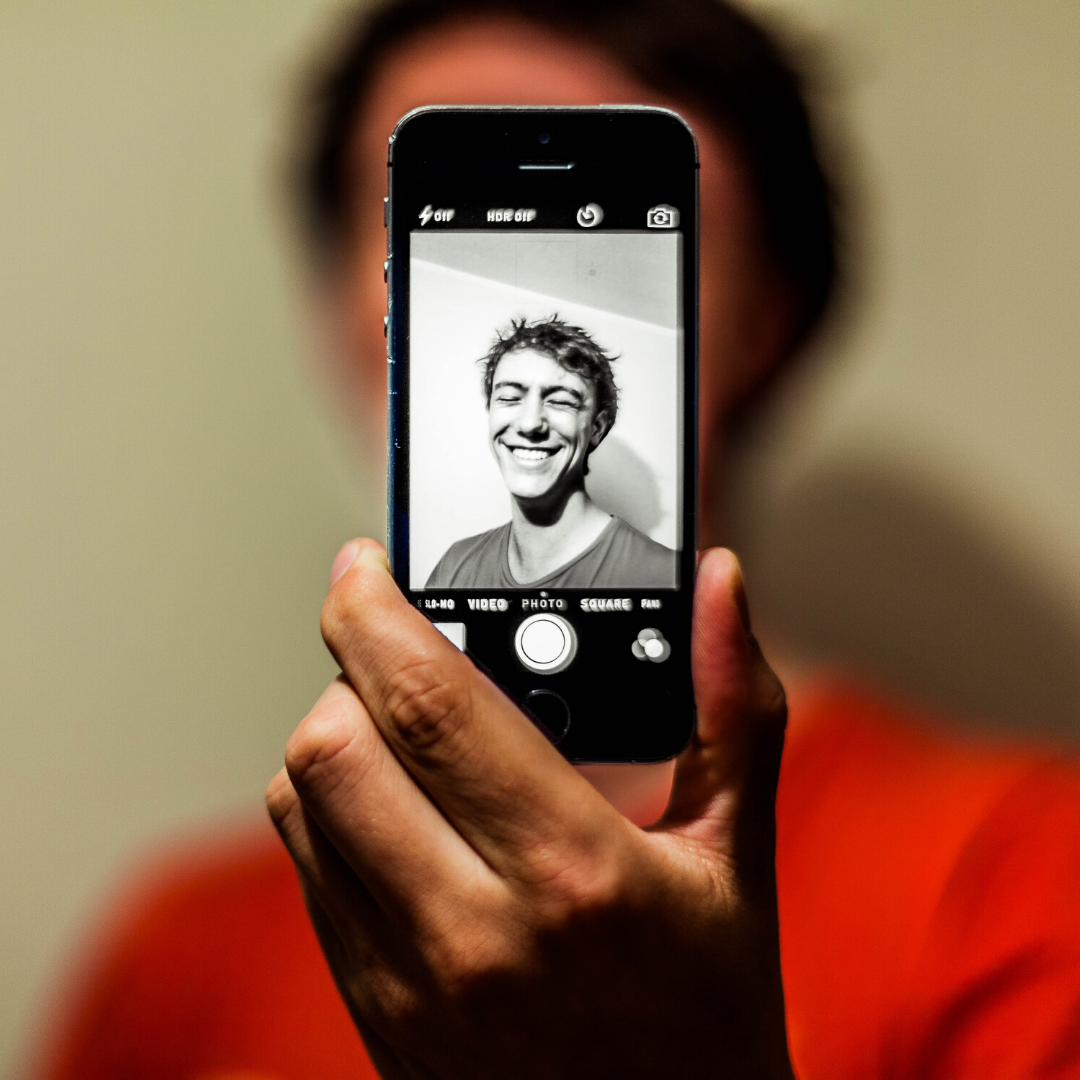 zdjęcie przedstawiające chłopaka robiącego selfie telefonem komórkowym